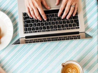 Hands Typing on Laptop with Coffee